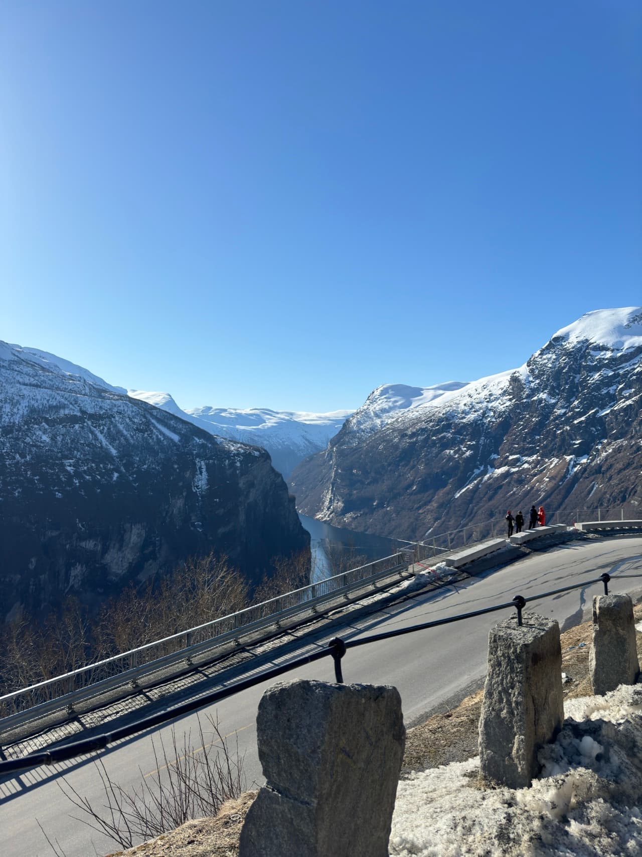 Spectacular Geirangerfjord viewpoint with towering mountains and road winding up the cliffside