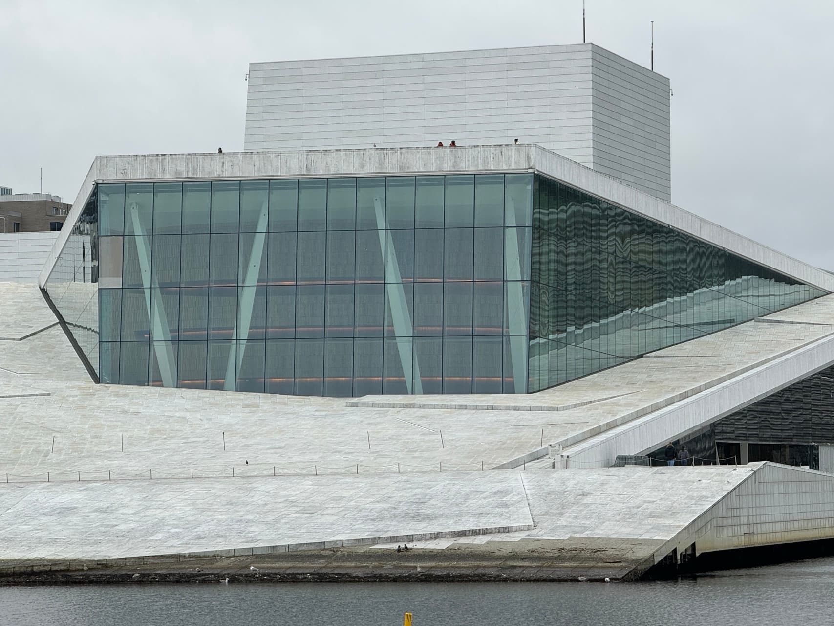 Oslo Opera House's dramatic, angled facade reflects the sky and water