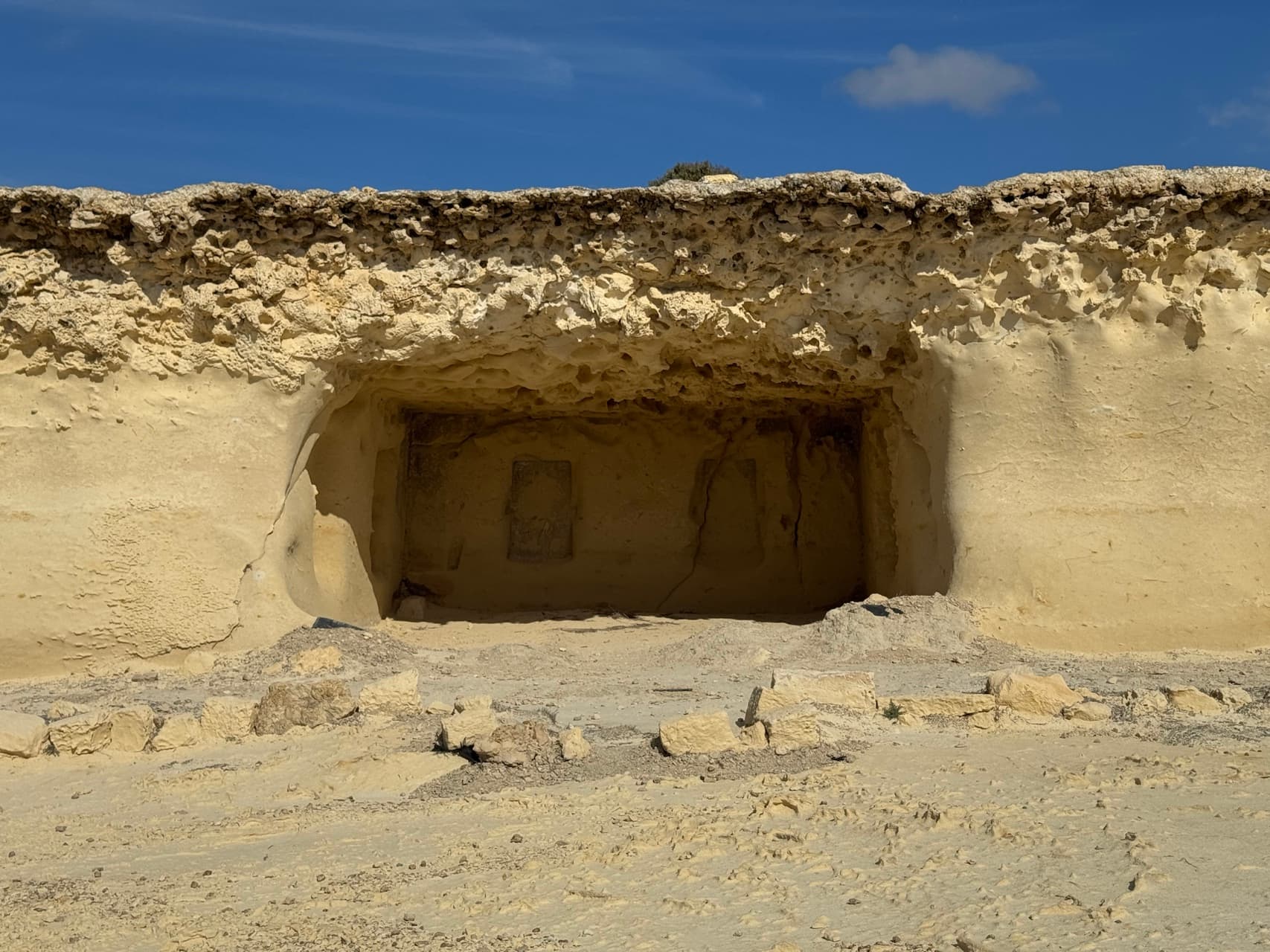 Ancient Maltese temple entrance amidst sandy terrain