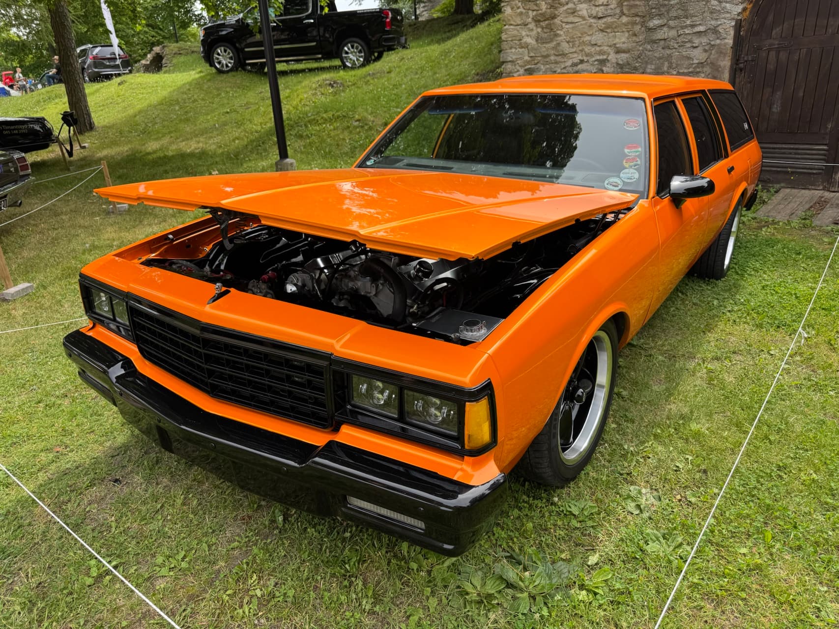 Restored classic car, orange paint, showing open hood detail
